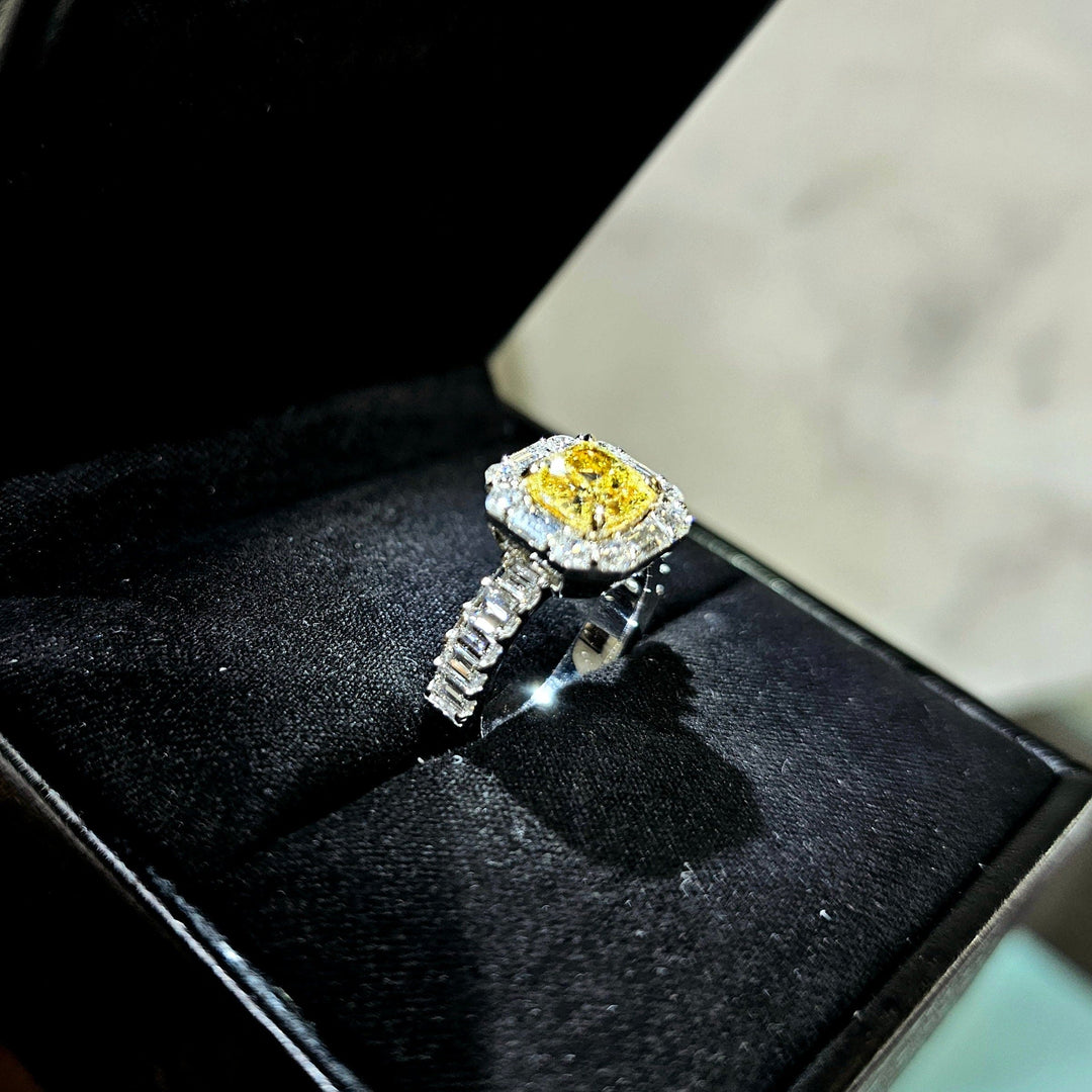 Cushion Yellow diamond with Halo baguette and Round cut Ring in white gold in a ring box side profile