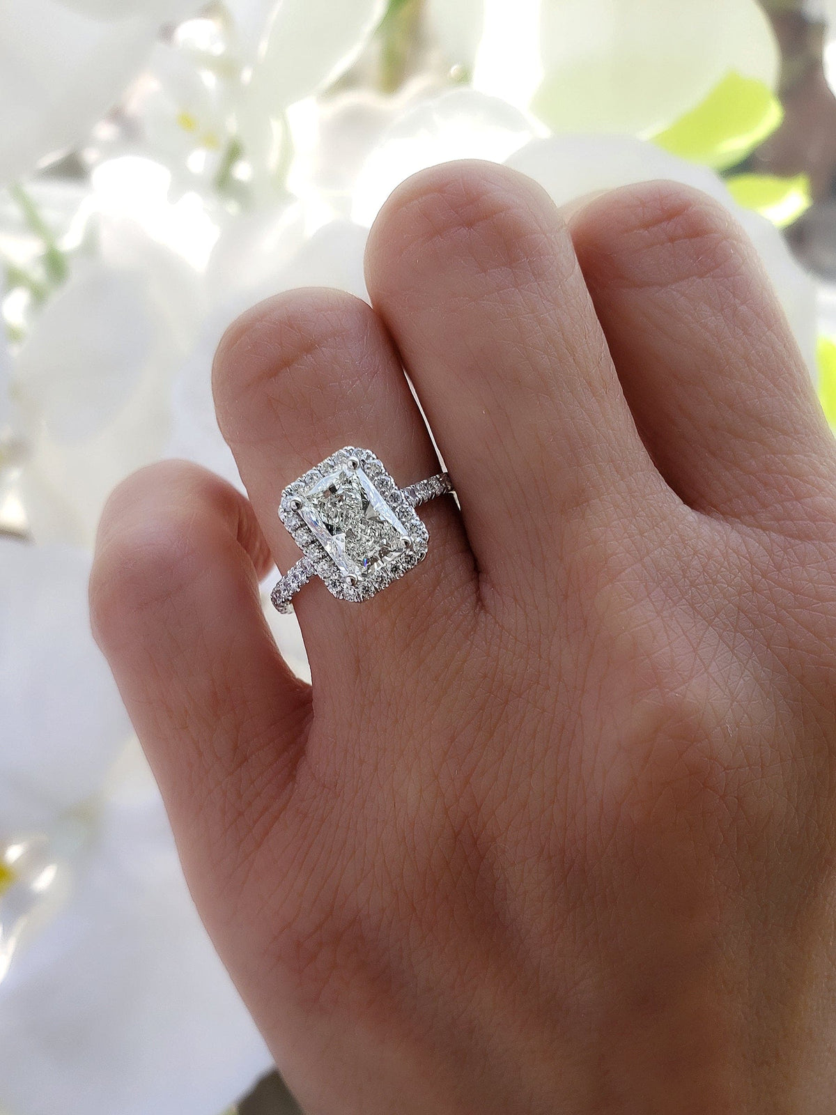 Rectangle halo radiant cut engagement ring on hand