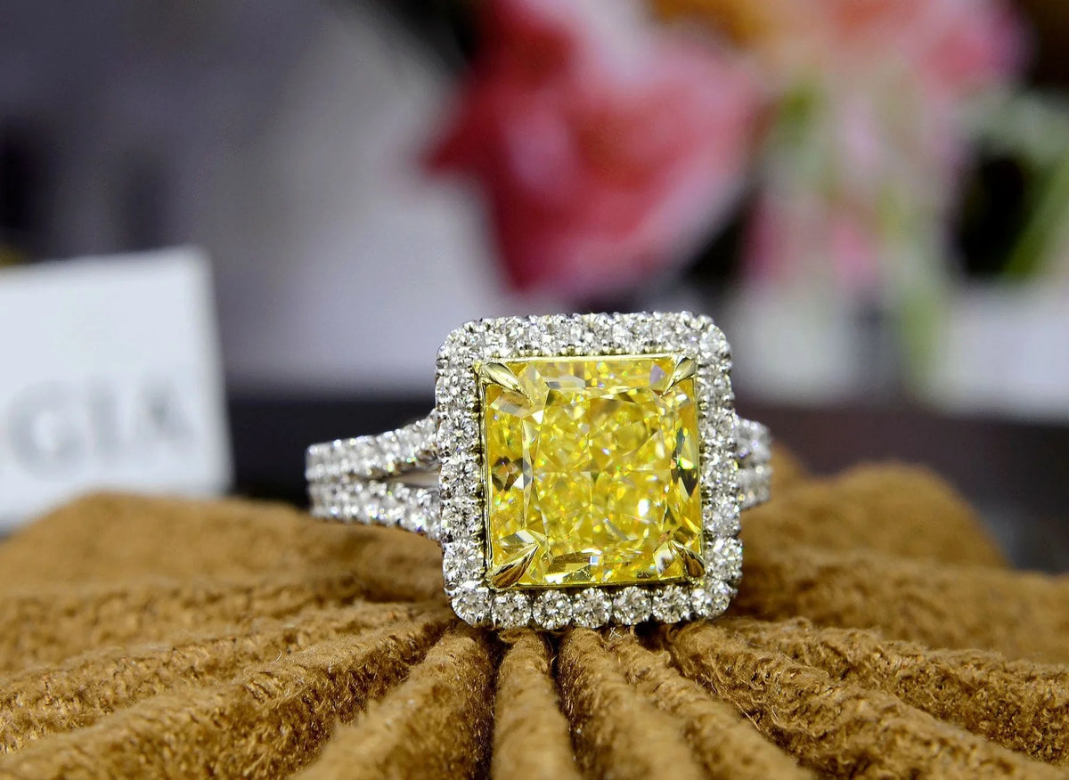 Square radiant cut yellow diamond set at the center of a halo split‑shank ring, crafted in white gold and secured with yellow‑gold prongs