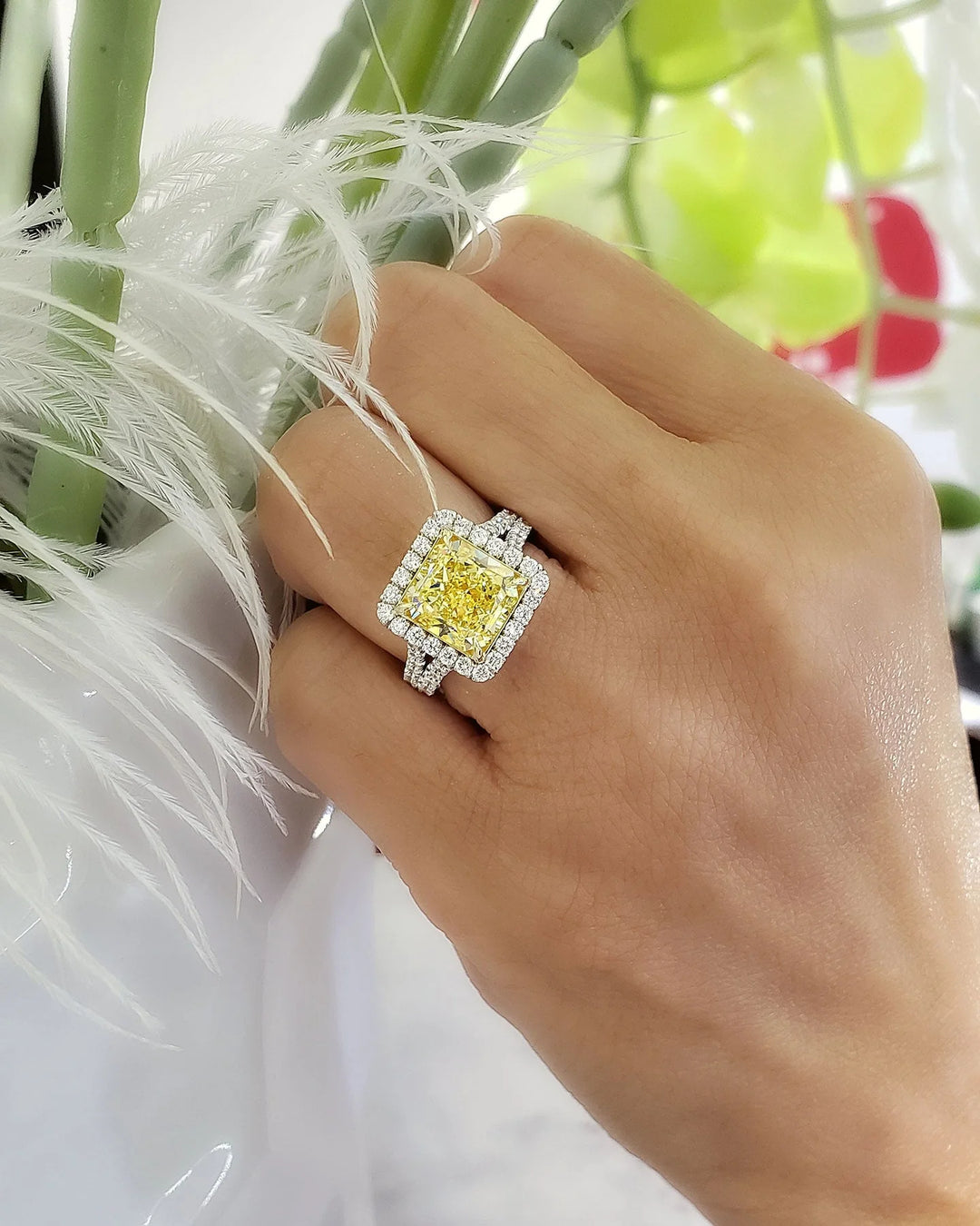 square radiant cut yellow diamond set at the center of a halo split‑shank ring, crafted in white gold and secured with yellow‑gold prongs on model's ring finger