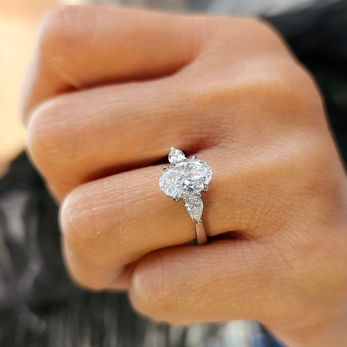 Oval cut with pear cut diamond 3 stone ring on finger side2 view