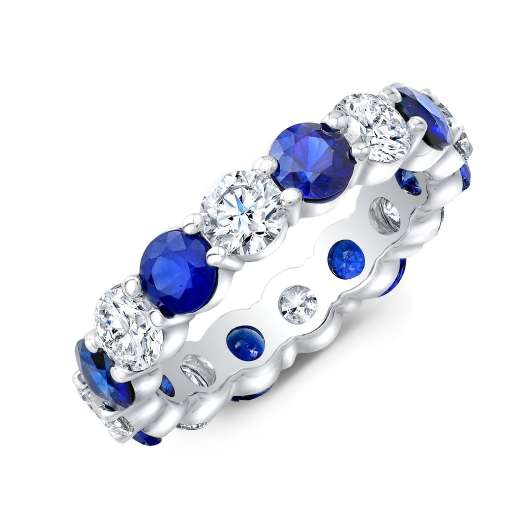 white gold eternity ring with blue and clear gemstones on a white background