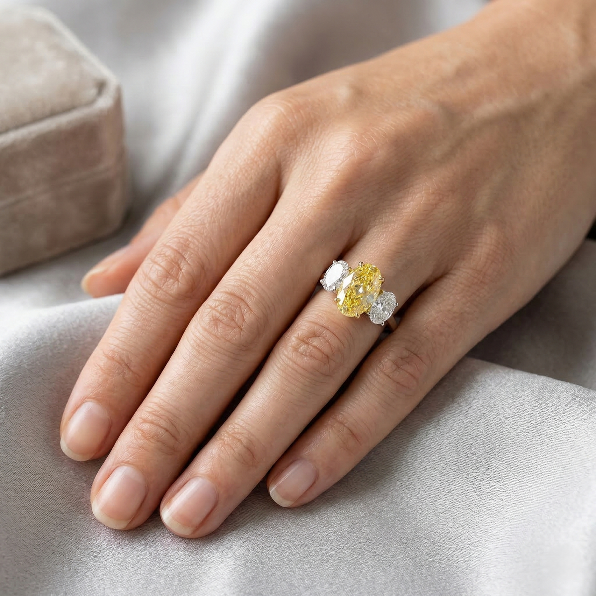 3 stone oval cut canary center side white diamonds on model's hand