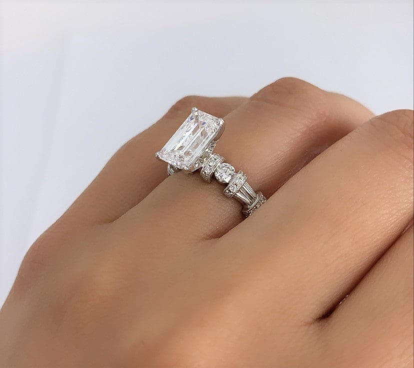 Emerald, baguette & round engagement ring on hand