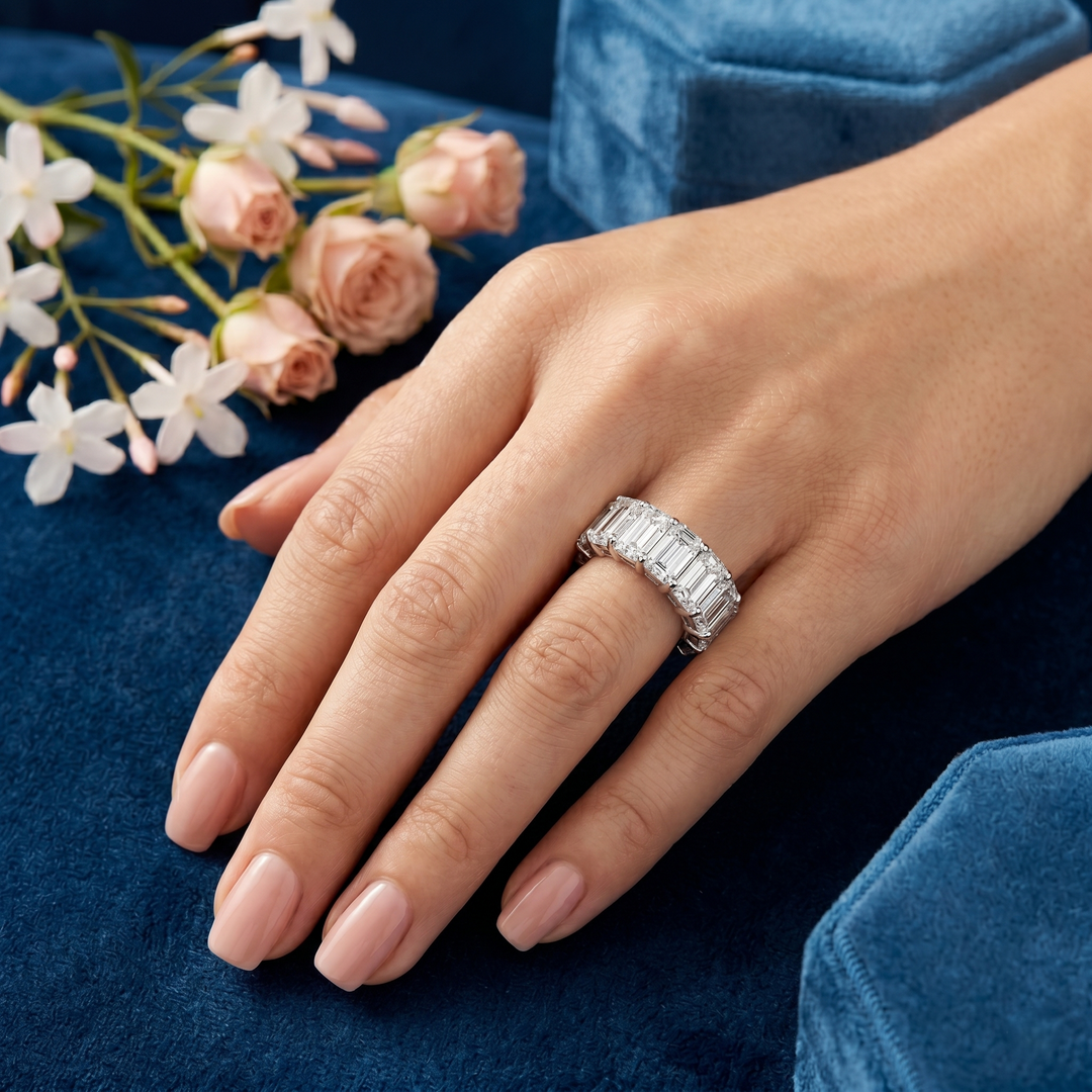 Hand wearing a diamond ring with flowers in the background