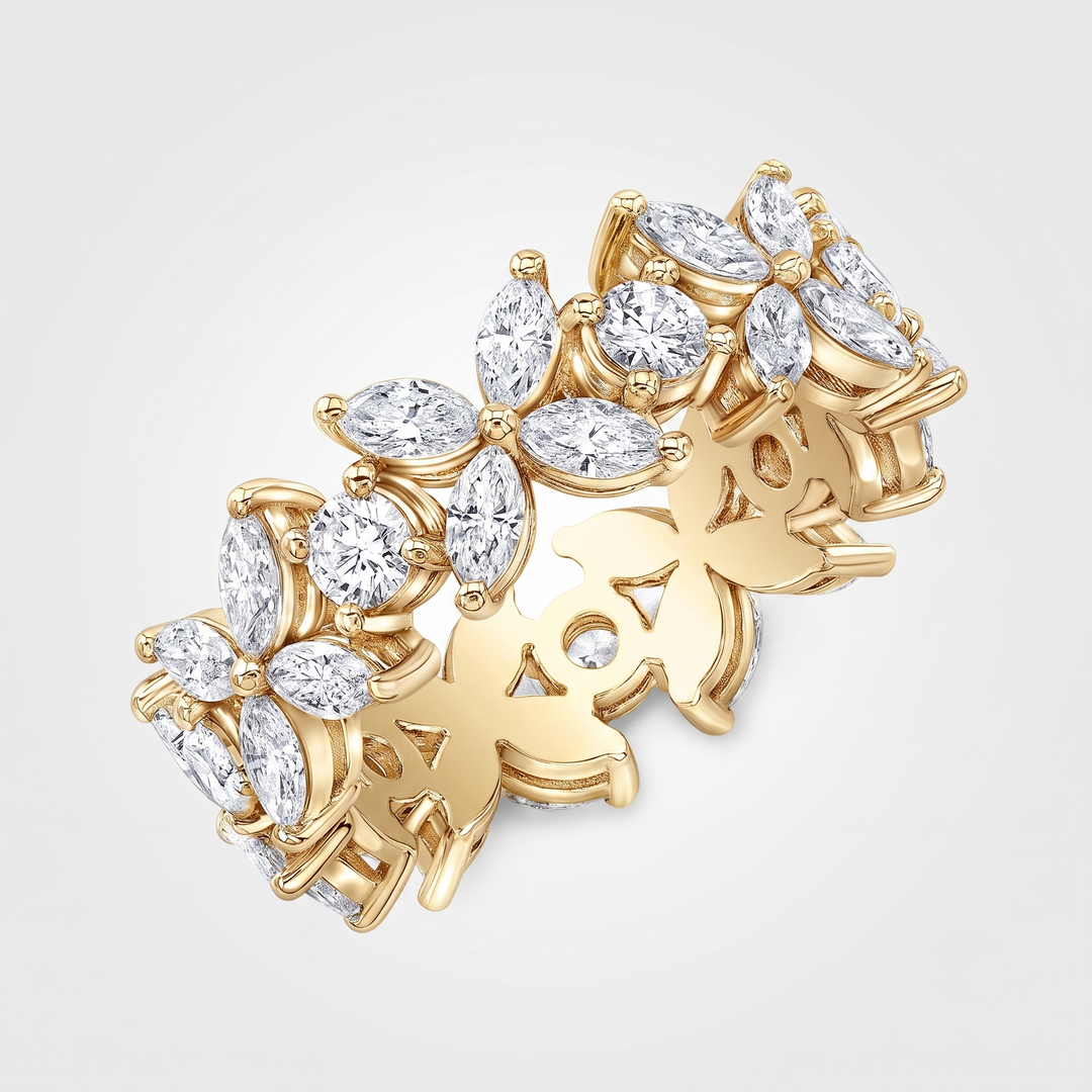 A yellow gold ring featuring a continuous pattern of stylized flower buds and leaves, each set with clear marquise and round-cut diamonds, shown on a light gray background.