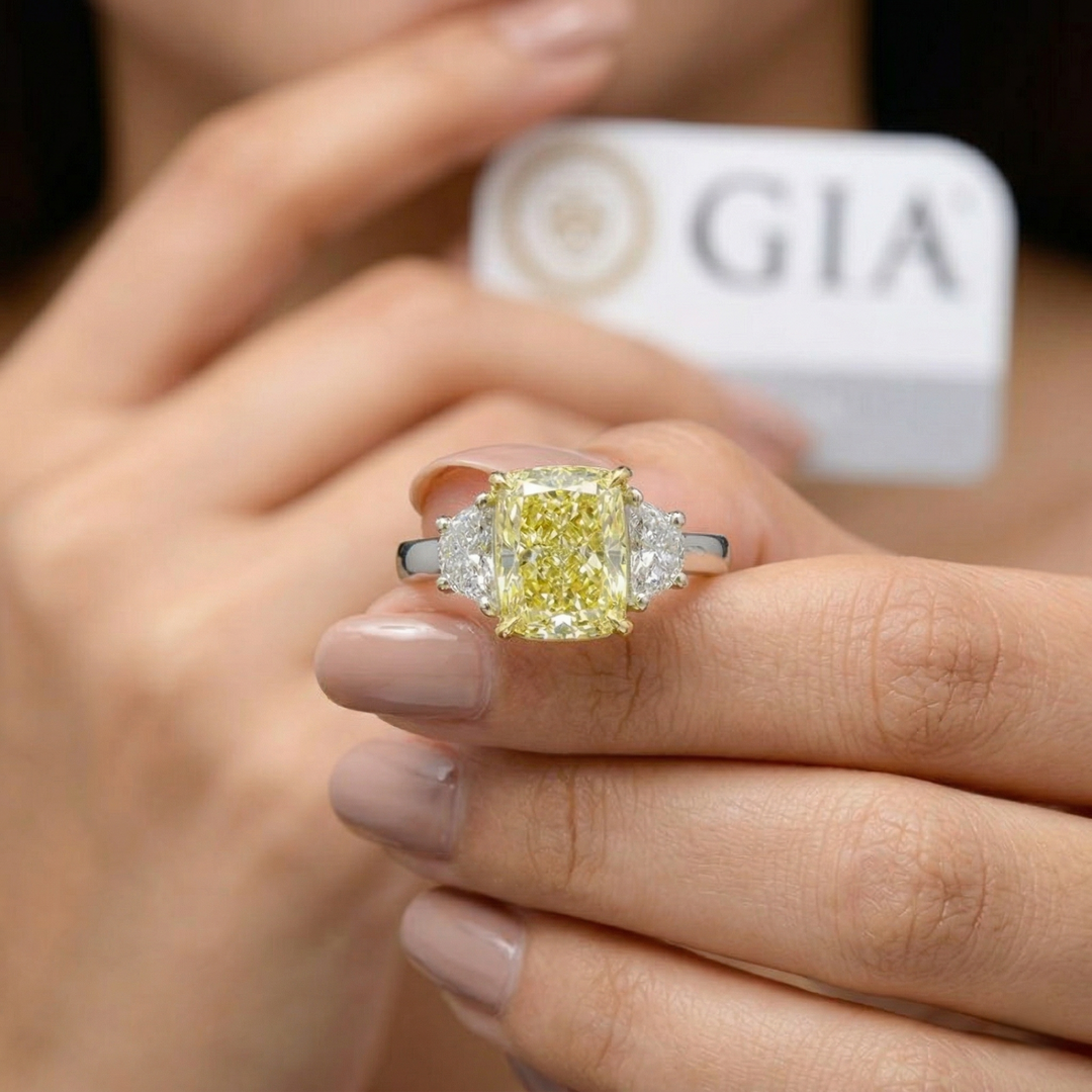 Yellow diamond ring on a finger with GIA certification in the background