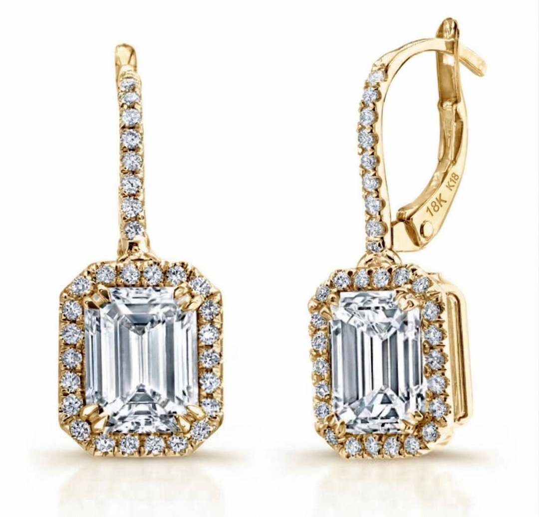 Gold earrings with emerald-cut gemstones and diamond accents on a white background