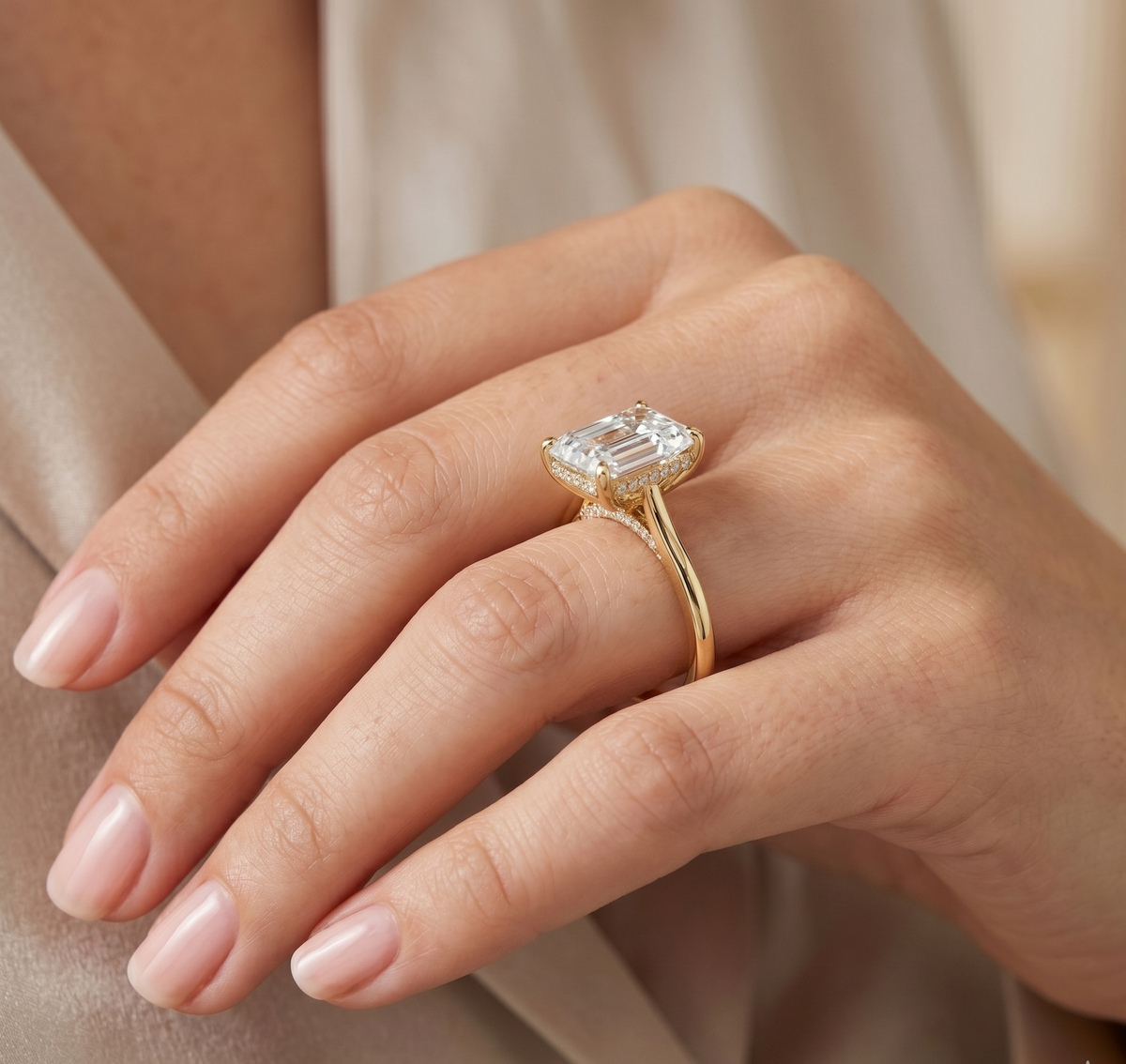 Hidden halo emerald cut center diamond ring in yellow gold on model's ring finger