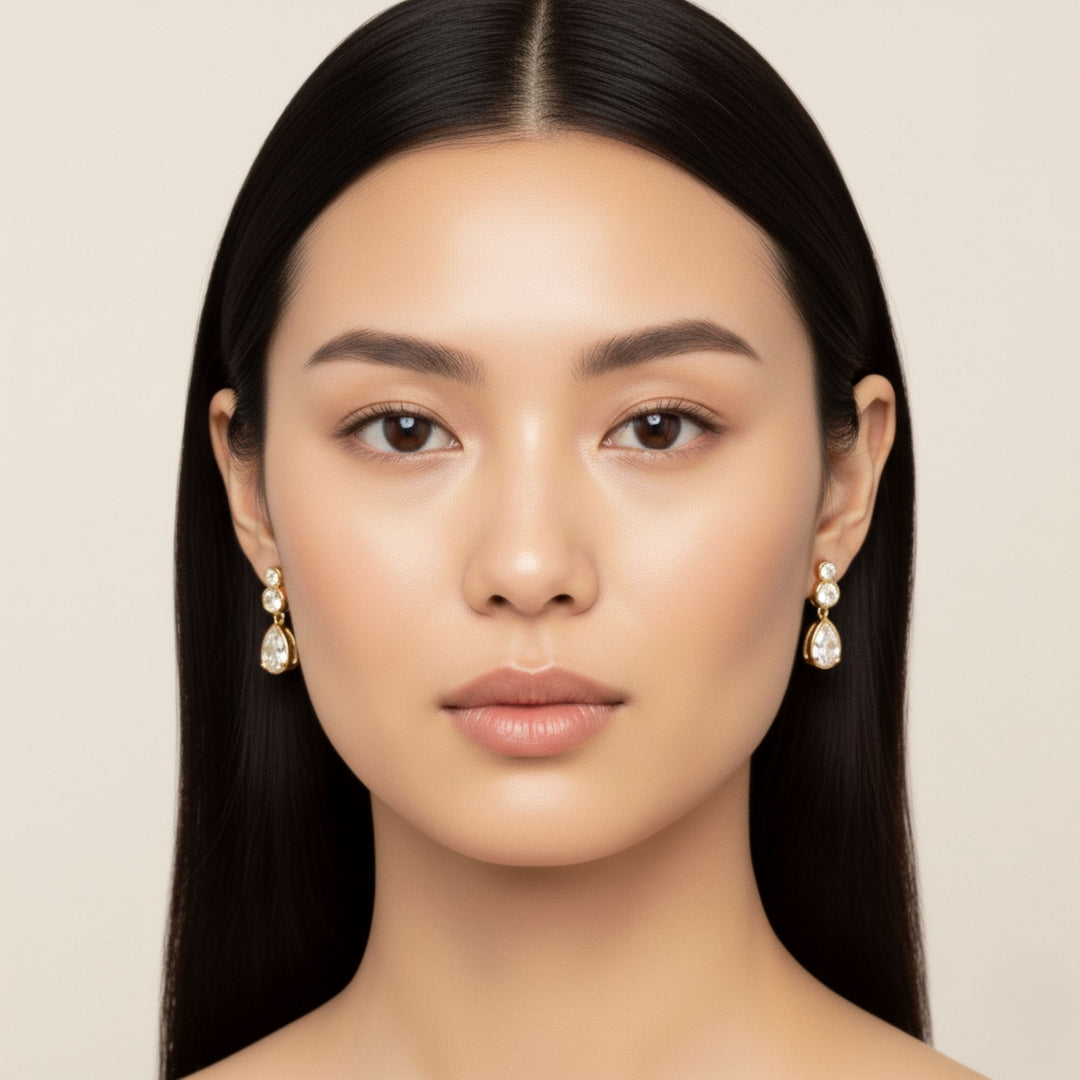 Pear & Round Diamond Bezel Set Dangling Earrings in yellow gold worn by a lady model