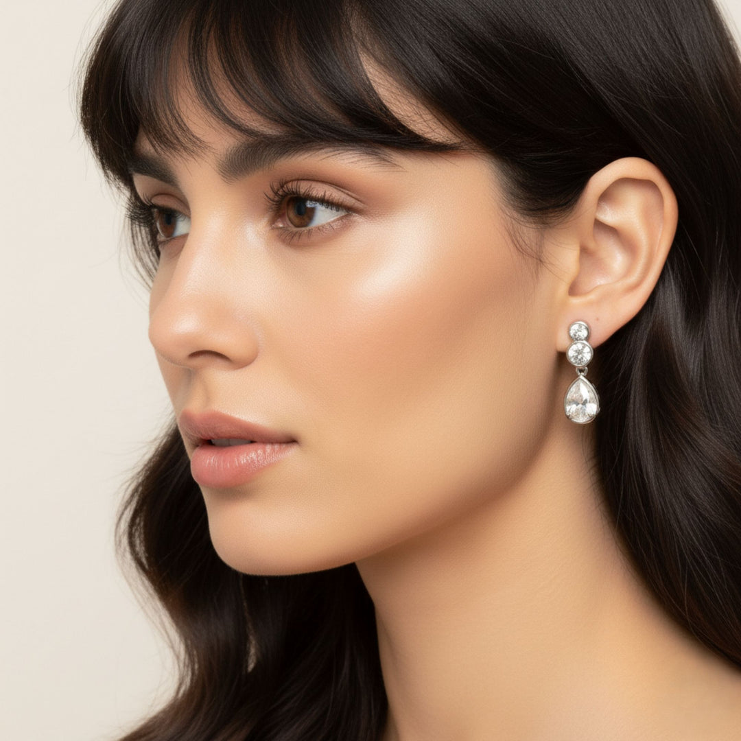 Pear & Round Diamond Bezel Set Dangling Earrings in white gold worn by a lady model