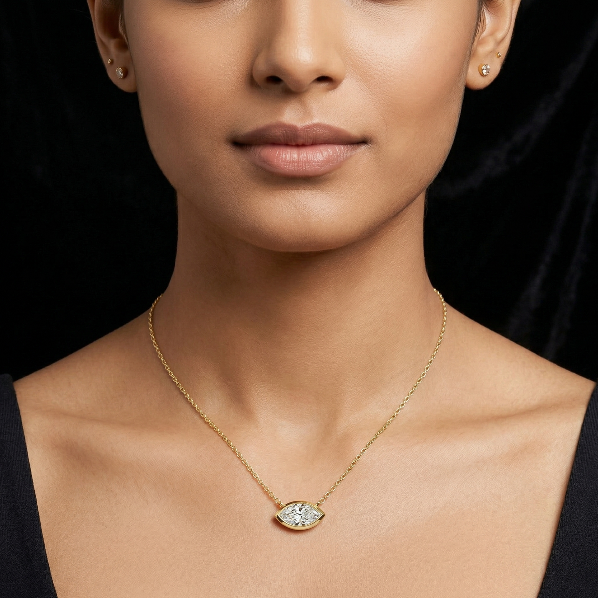 Woman wearing a gold marquise diamond necklace with a diamond pendant against a black background
