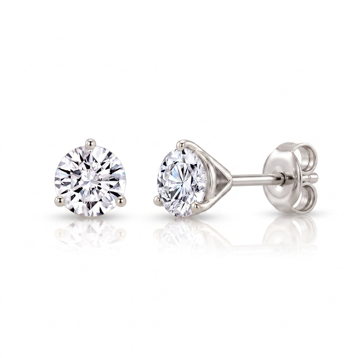 A pair of 3 prong martini round cut diamond stud earrings in a white gold setting, shown from both front and side angles on a clean white background with soft reflections