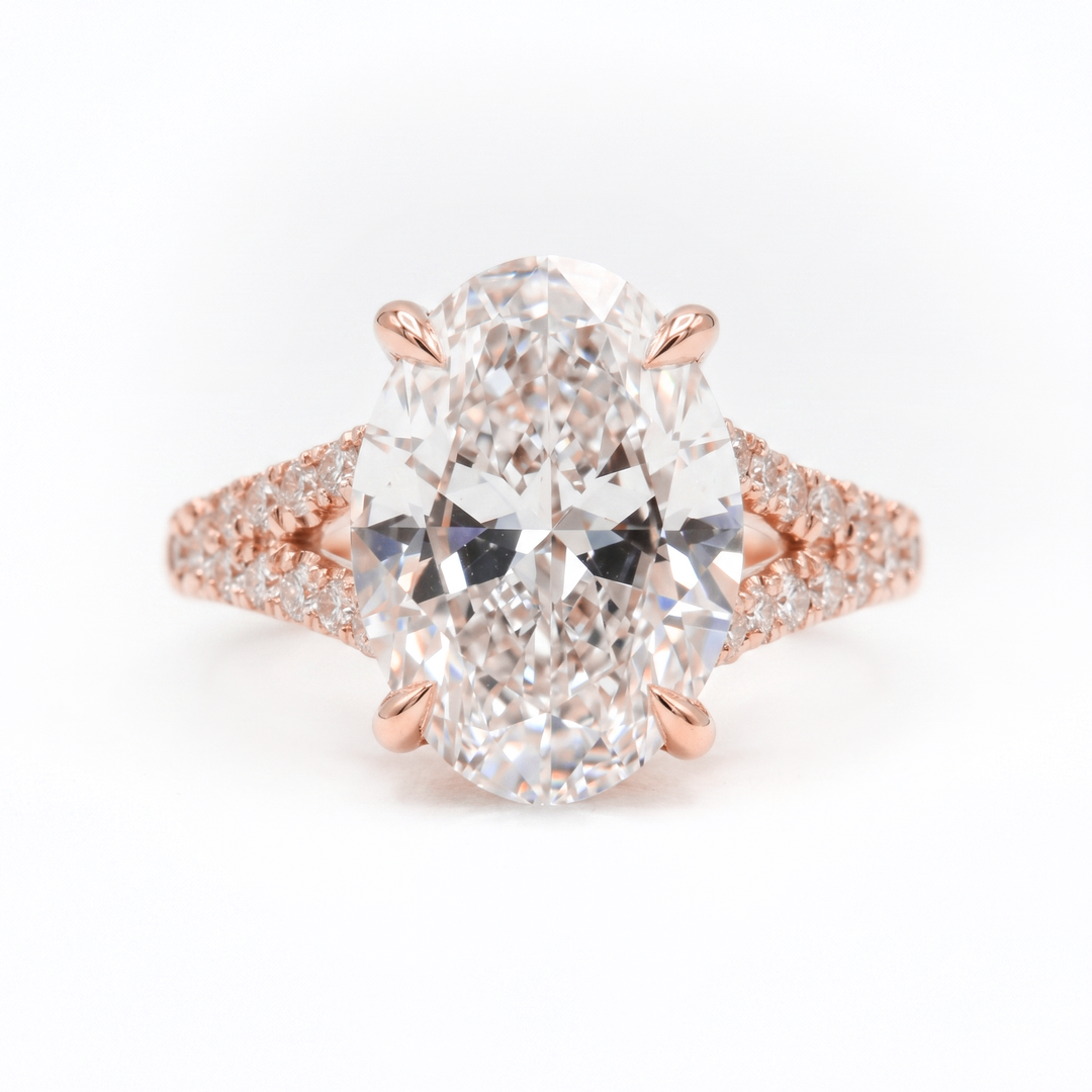 An oval-cut diamond engagement ring in a rose gold setting with pavé diamond accents on the band, shown against a plain white background.