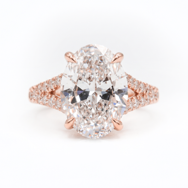 An oval-cut diamond engagement ring in a rose gold setting with pavé diamond accents on the band, shown against a plain white background.