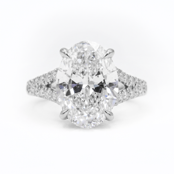 An oval-cut diamond engagement ring with a brilliant solitaire center stone and pavé-set diamond shoulders on a white background.