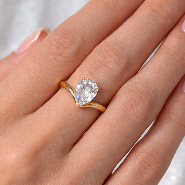 Pear Cut Chevron Solitaire Engagement Ring in yellow gold worn on model's 3rd finger
