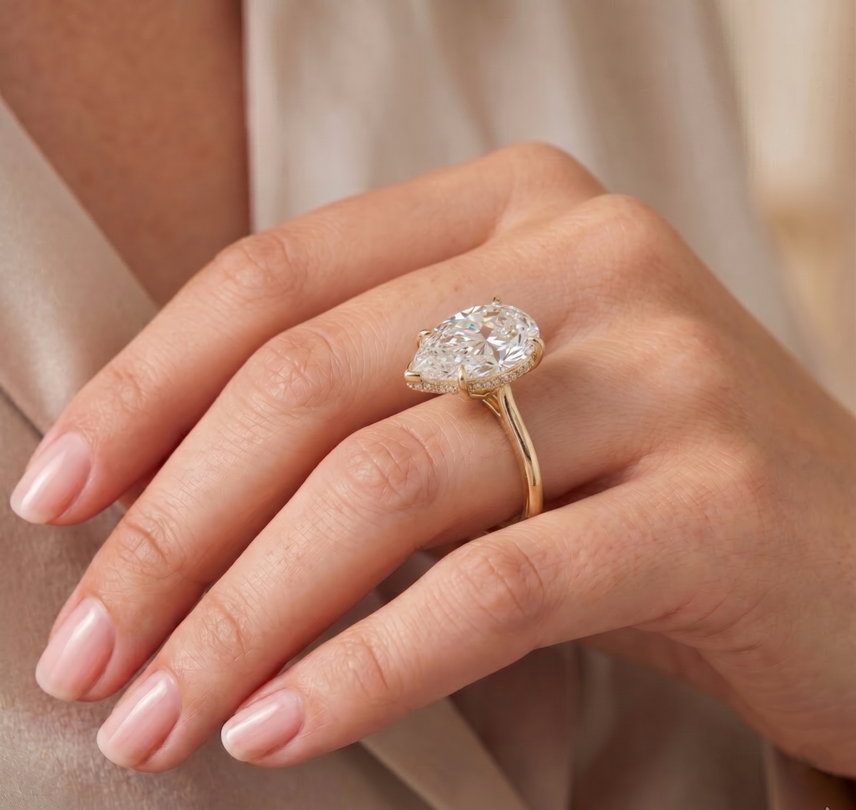 Pear cut hidden halo diamond ring in yellow gold on model's hand