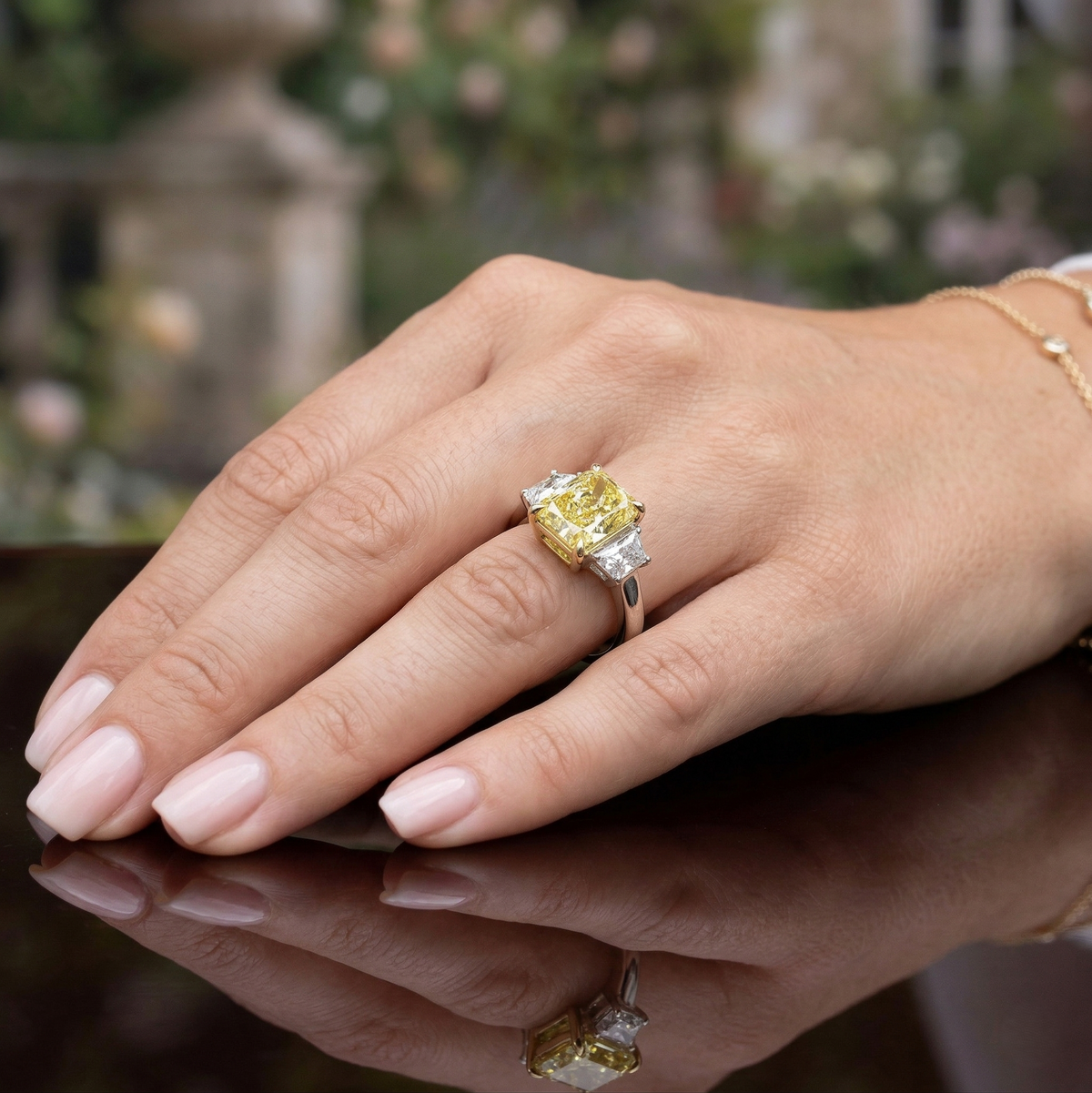 Three stone radiant canary elongated with trapezoids on the sides on model's hand