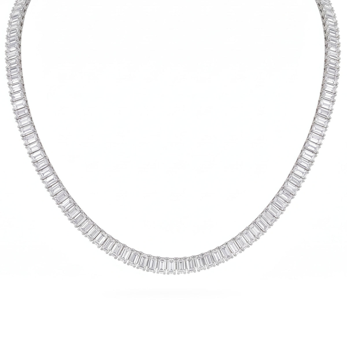 A white gold tennis necklace featuring emerald cut clear stones, in a solid white background