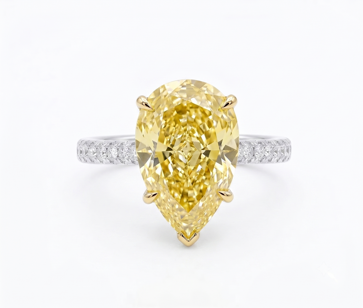 A pear cut yellow diamond ring with a yellow gold prong setting and a white gold or platinum pavé band, shown on a clean white background