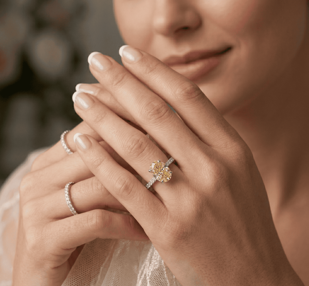 Close-up of a woman's hands wearing canary oval ring.
