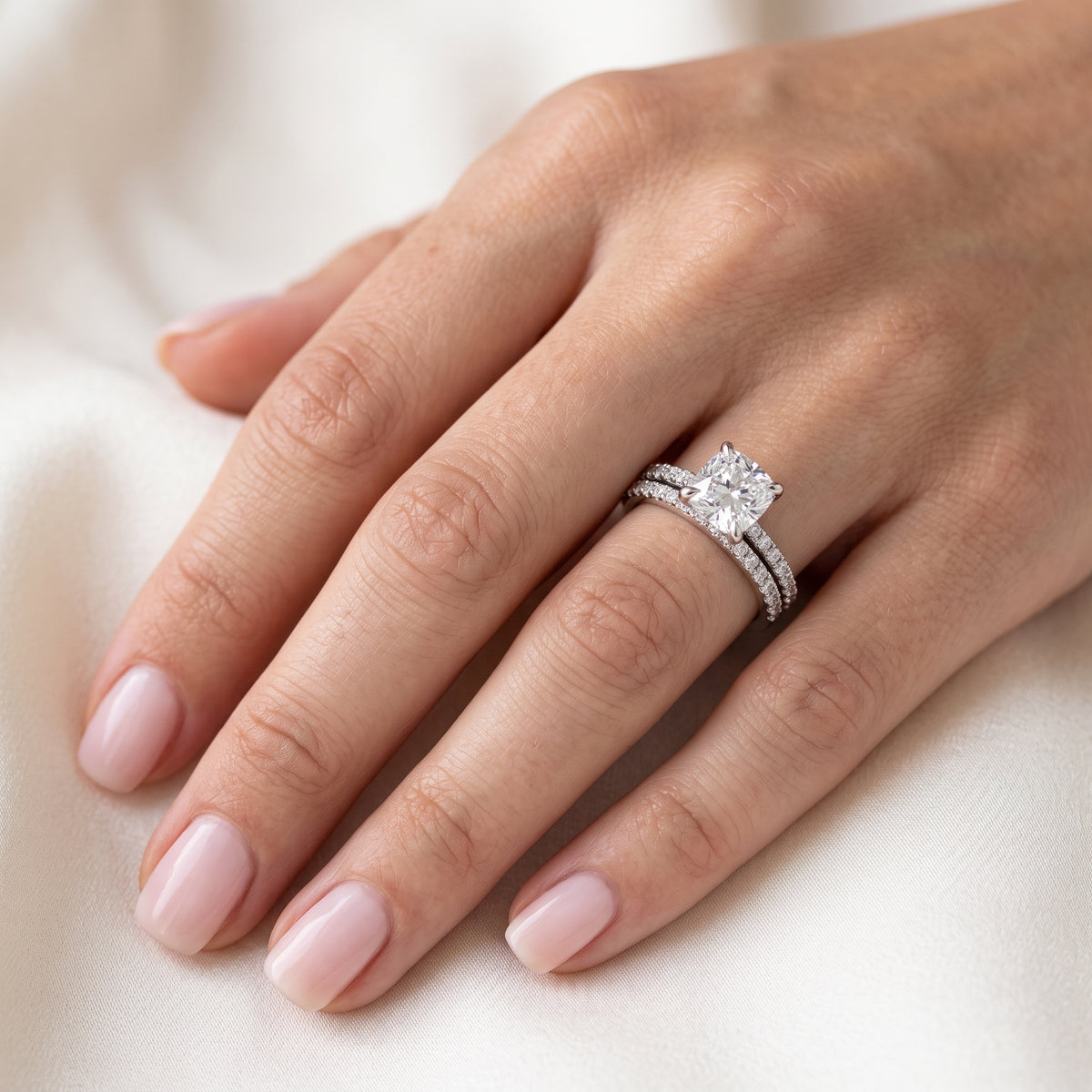 Cushion cut engagement ring and matching band on hand