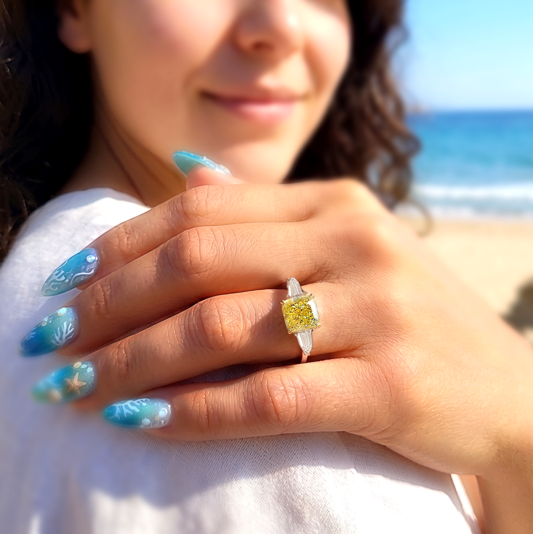 a lady with blue finger nails wearing a cushion yellow diamond ring with bullet cut  3 stone ring