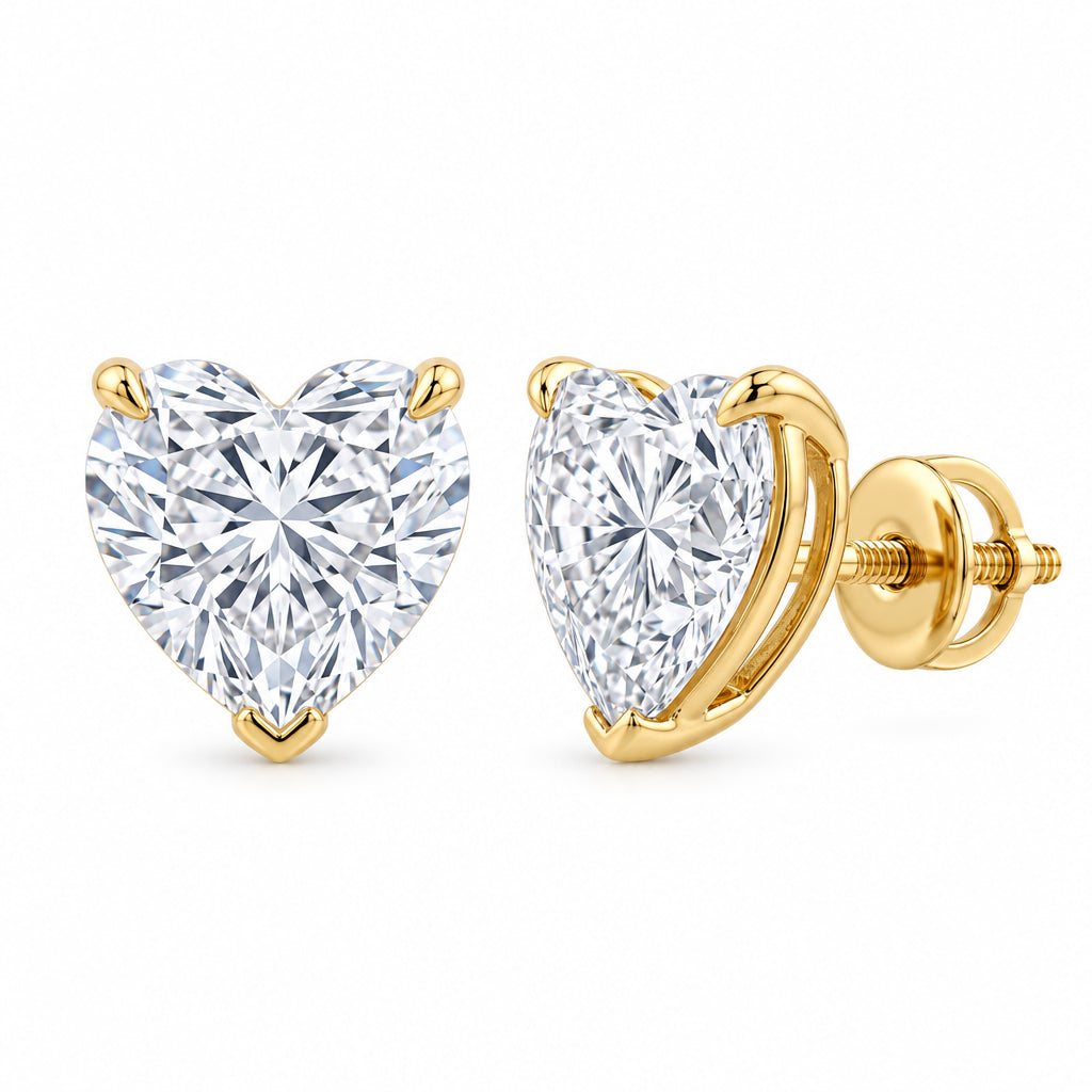 A pair of heart-shaped diamond stud earrings in yellow gold settings, shown from both front and side angles on a light gray reflective surface.