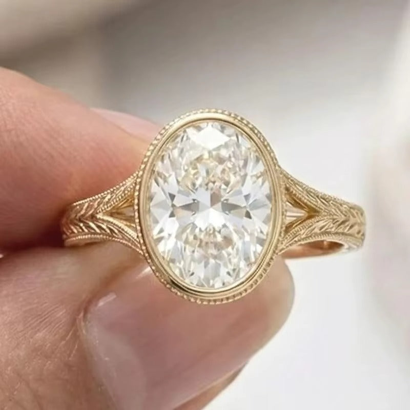 Oval bezel diamond with engraved split shank ring in yellow gold on hand