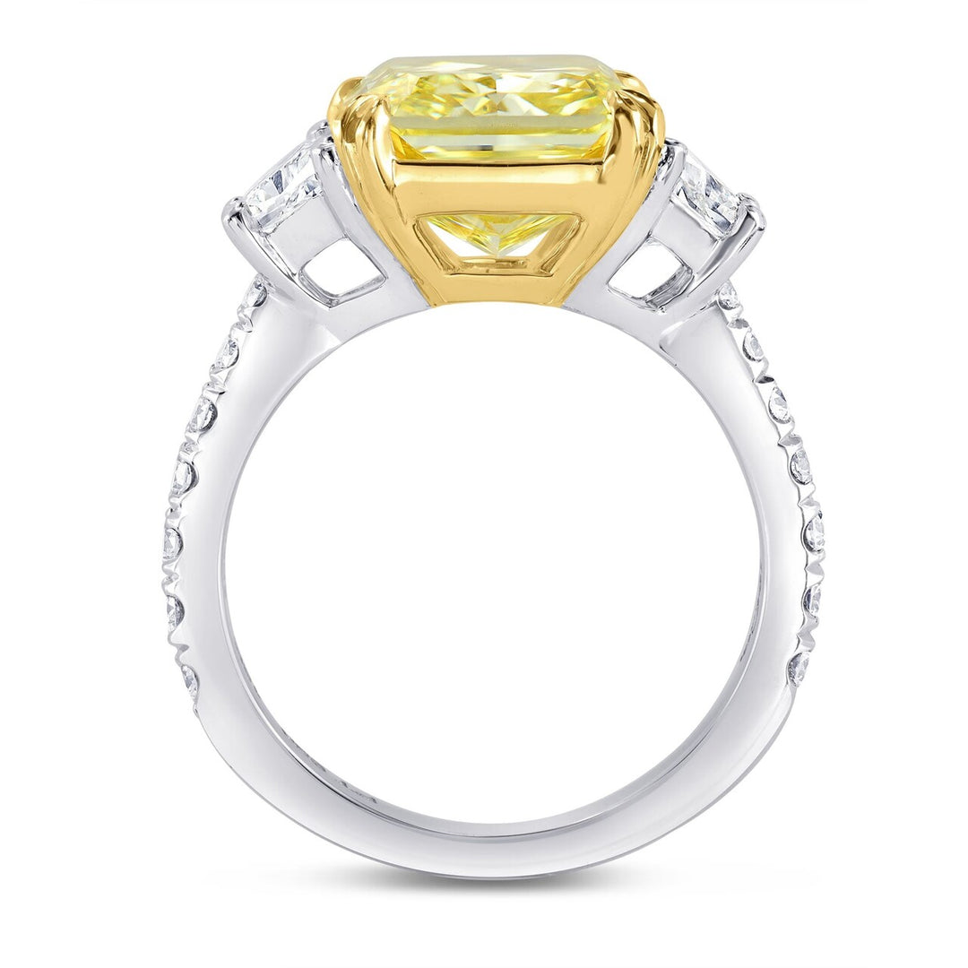 Side view of elongated radiant cut Yellow diamond ring with diamond-studded band on a white background