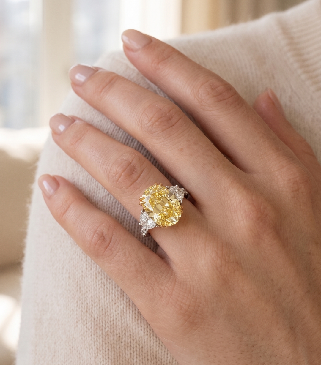 Hand wearing a yellow diamond ring with a blurred background