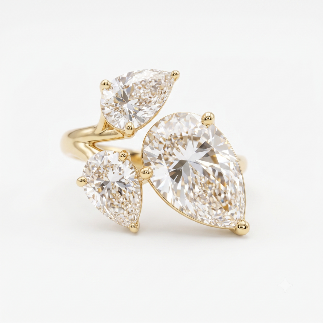 A yellow gold ring featuring three pear-cut clear gemstones in a cluster setting, photographed on a clean white background.