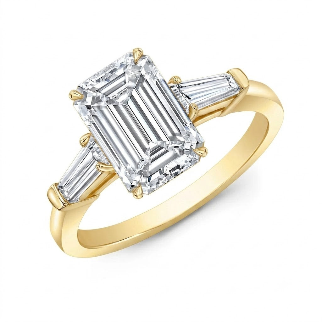 A yellow gold ring featuring a large emerald cut diamond center stone with two baguette cut diamonds on the shoulders, set against a plain white background