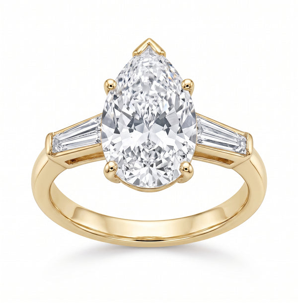 A yellow gold ring featuring a large pear-cut center stone with baguette side stones, shown on a clean white background.