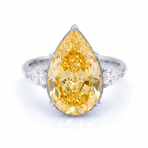 A pear-cut yellow diamond ring set in a white gold band with small pear cut diamonds on either side, shown on a clean white background.