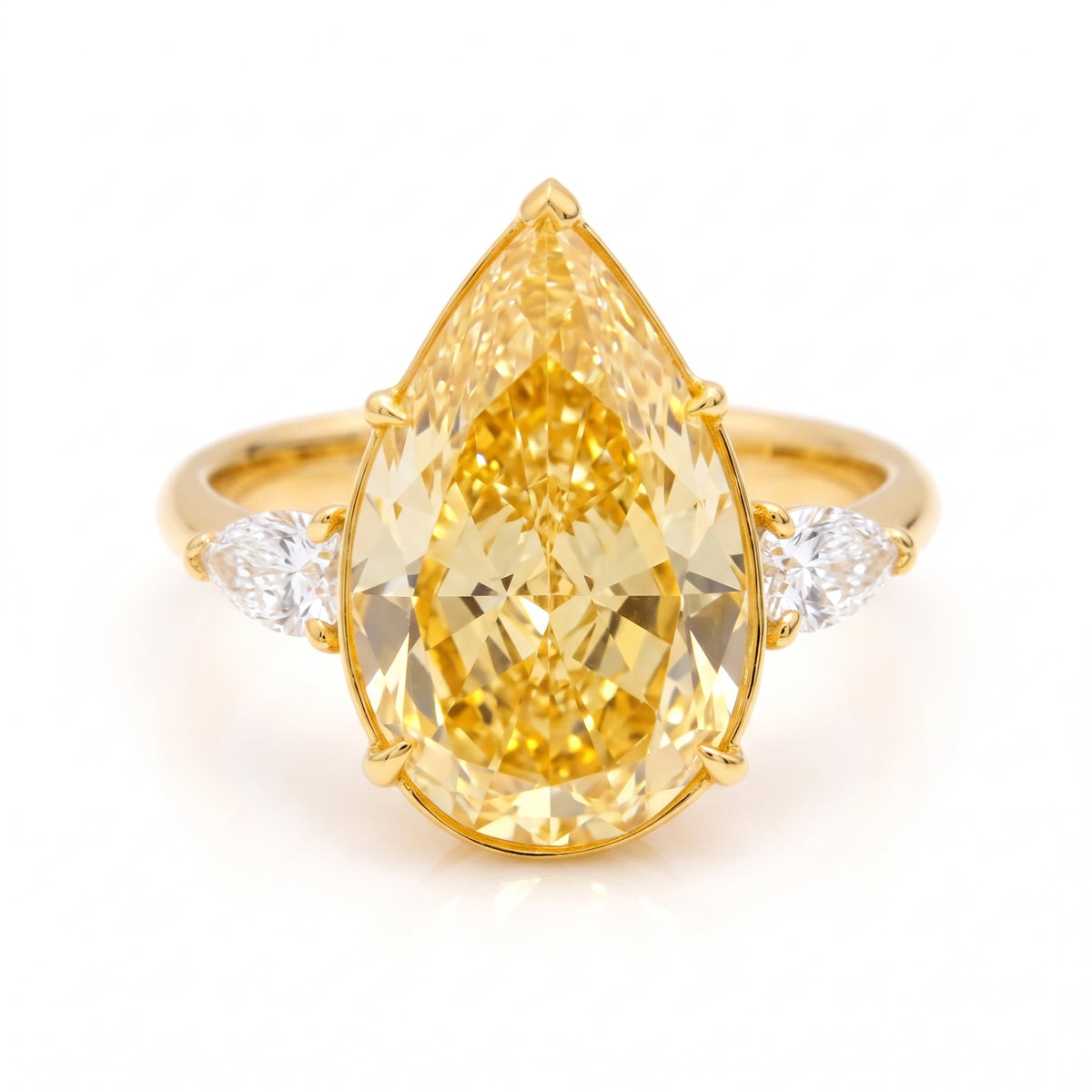 A yellow gold ring featuring a large pear cut yellow diamond center stone with two small round diamonds on either side of the band, set against a clean white background