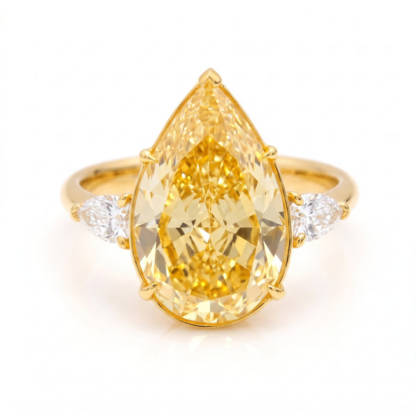 A yellow gold ring featuring a large pear-cut yellow diamond center stone with two small round diamonds on either side of the band, set against a clean white background.