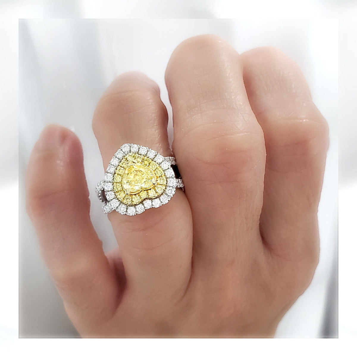 Heart shape fancy yellow canary halo engagement ring on finger