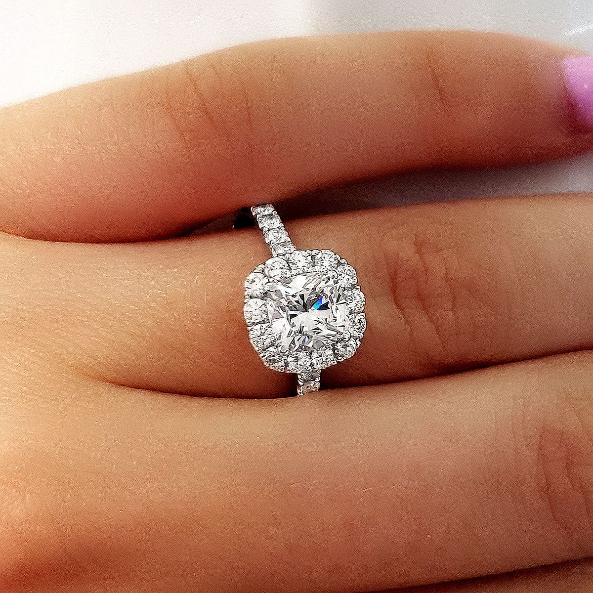 Cushion cut halo engagement ring on hand
