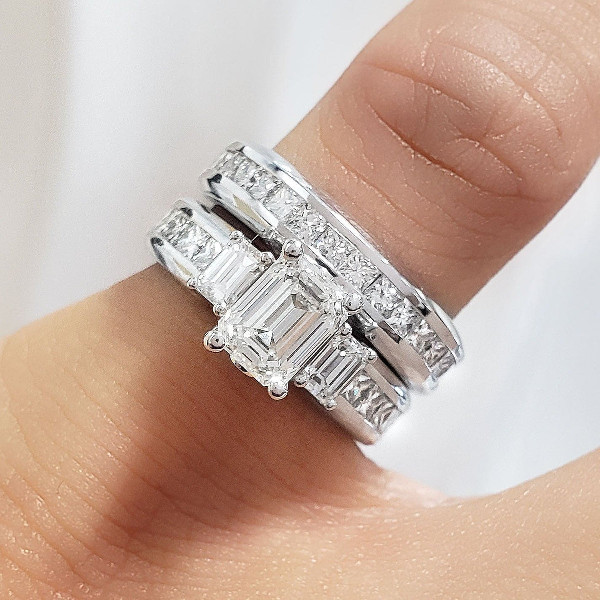 3 stone emerald cut engagement ring set on finger