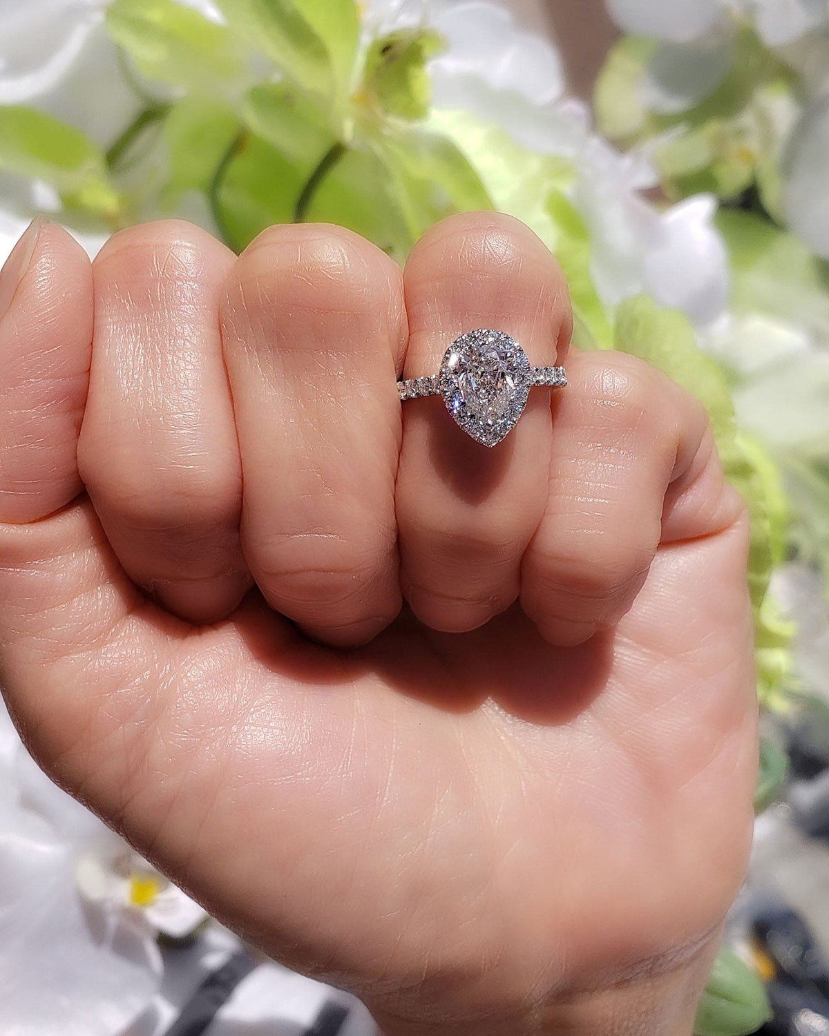 Teardrop pear halo engagement ring set on hand