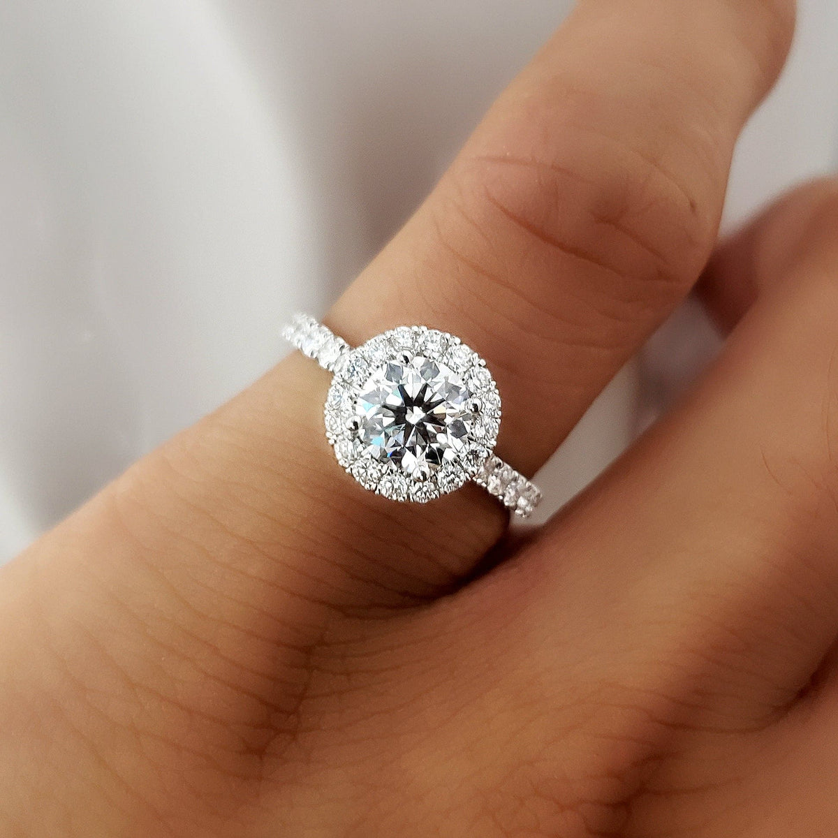 Round halo engagement ring on hand