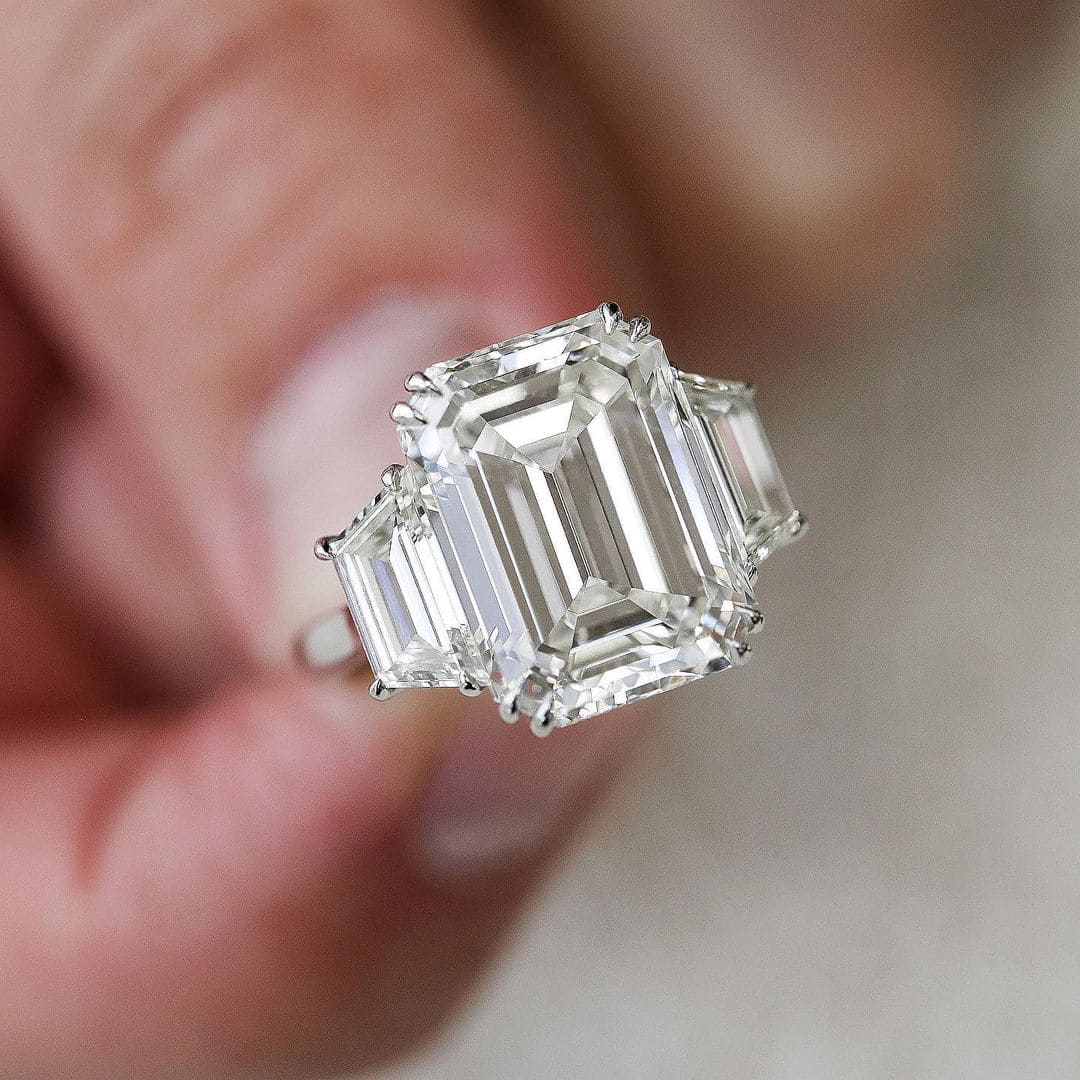 3 stone emerald cut engagement ring & trapezoids on hand