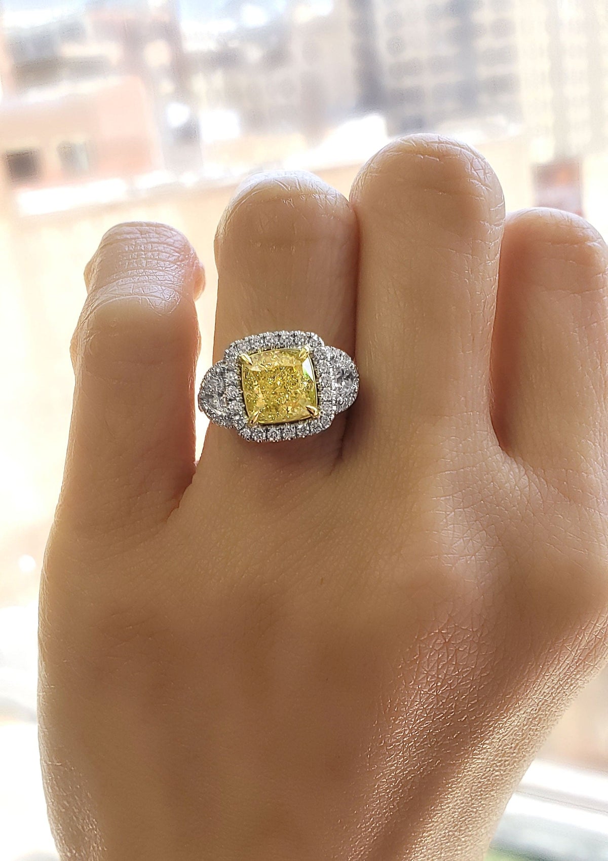 Yellow cushion & half moon halo engagement ring on hand