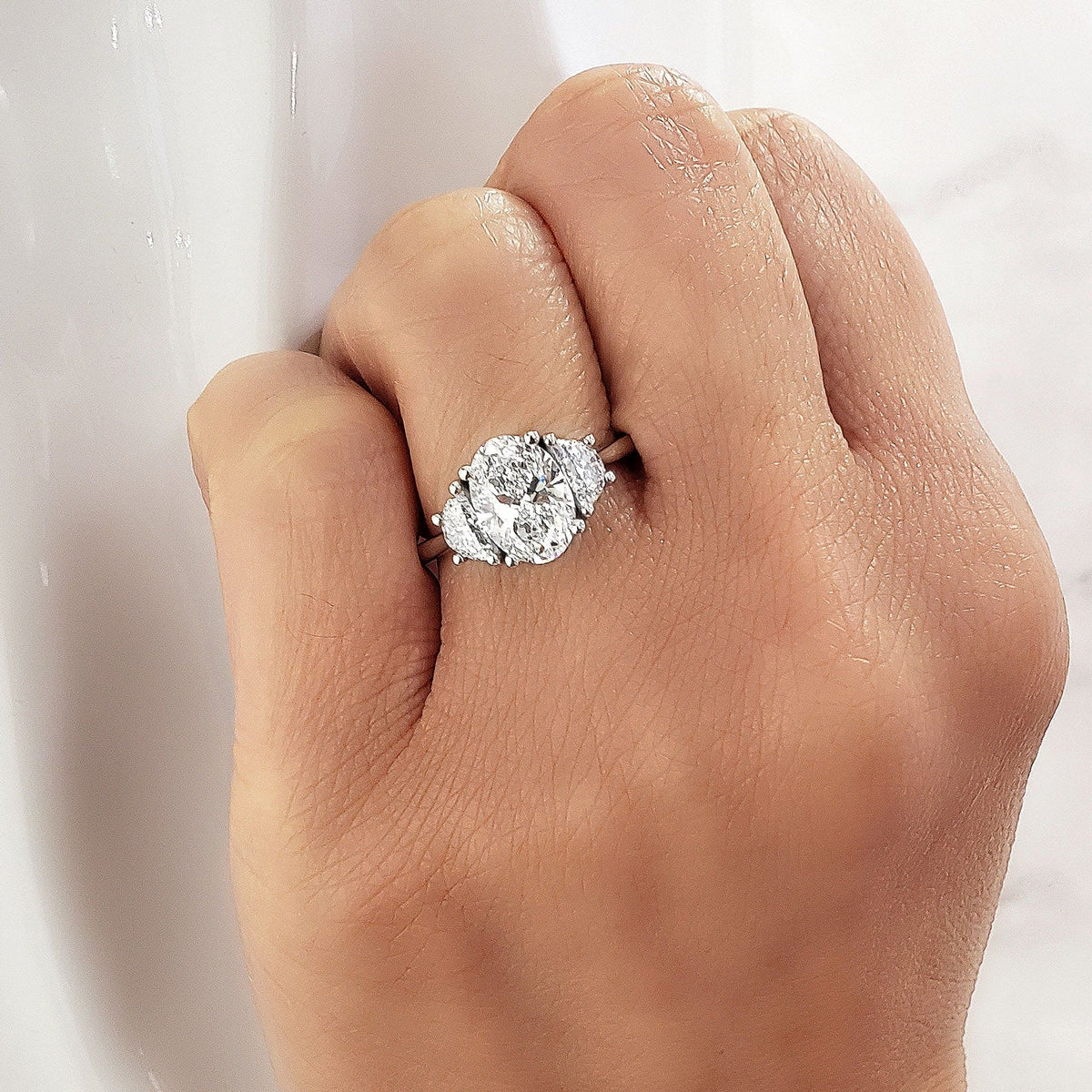 3 stone oval engagement ring with half moons on hand