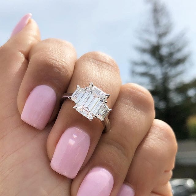 Emerald cut 3 stone diamond ring on hand