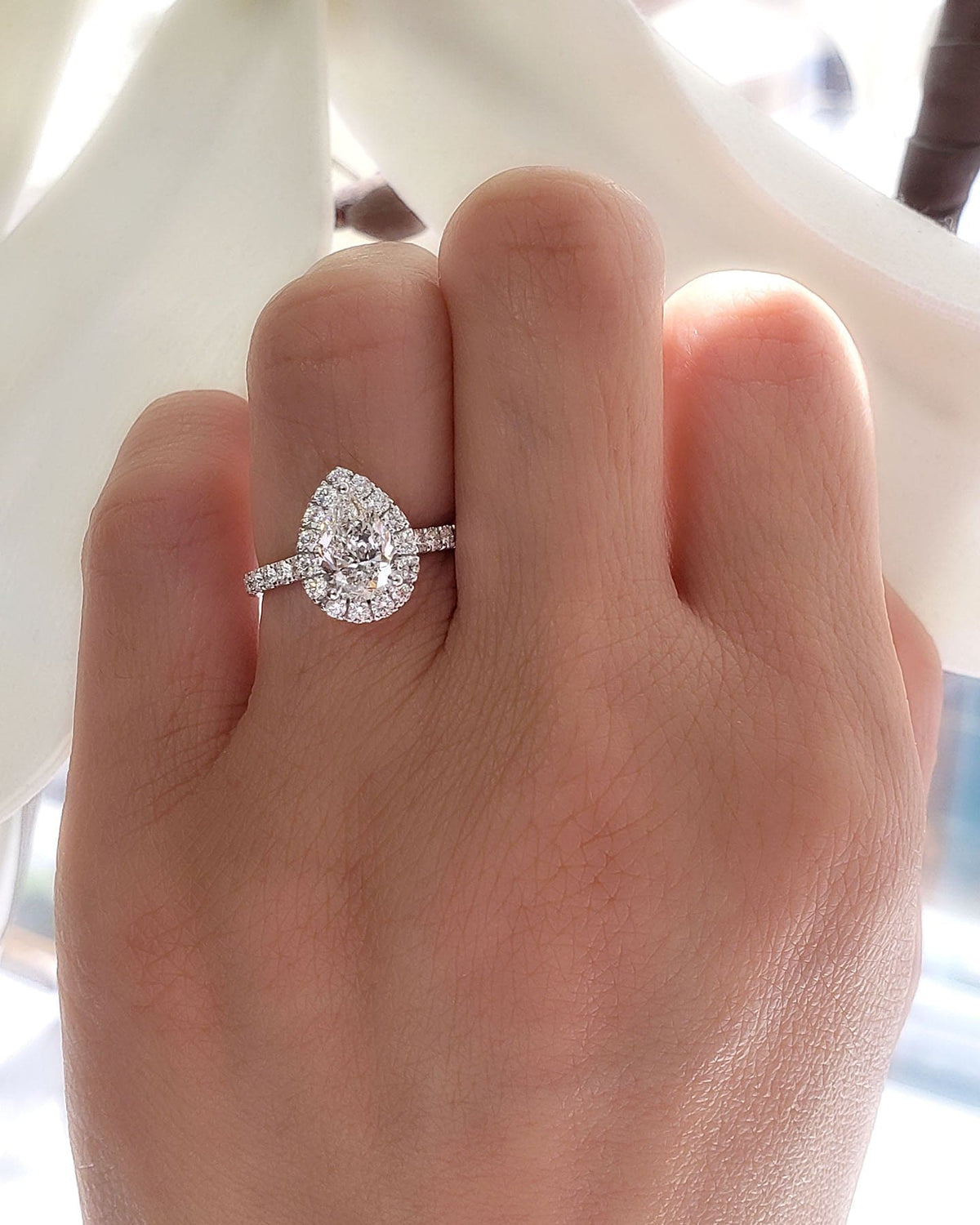 Halo teardrop pear cut engagement ring set on hand