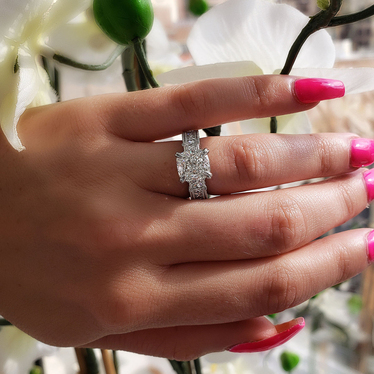 Cushion cut 3 stone diamond ring with accents on hand
