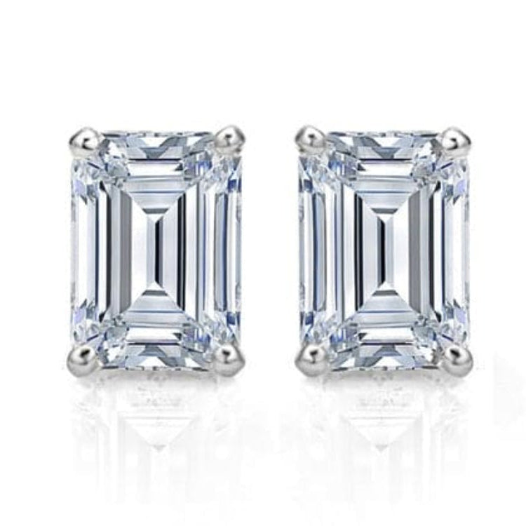 A pair of emerald cut diamond stud earrings set in a white gold band